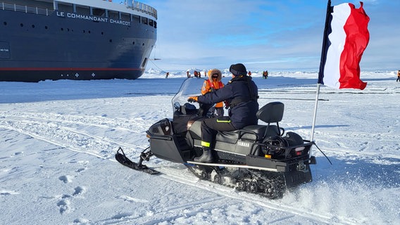 Ein Snowmobil fährt vor einer Yacht in der Arktis © NDR Foto: Sven Weniger