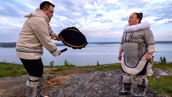 Ein Inuit-Pärchen in traditioneller Kleidung mit Pelzen singt am Flussufer (in Nunavik, Quebec) © NDR Foto: Achill Moser und Aaron Moser