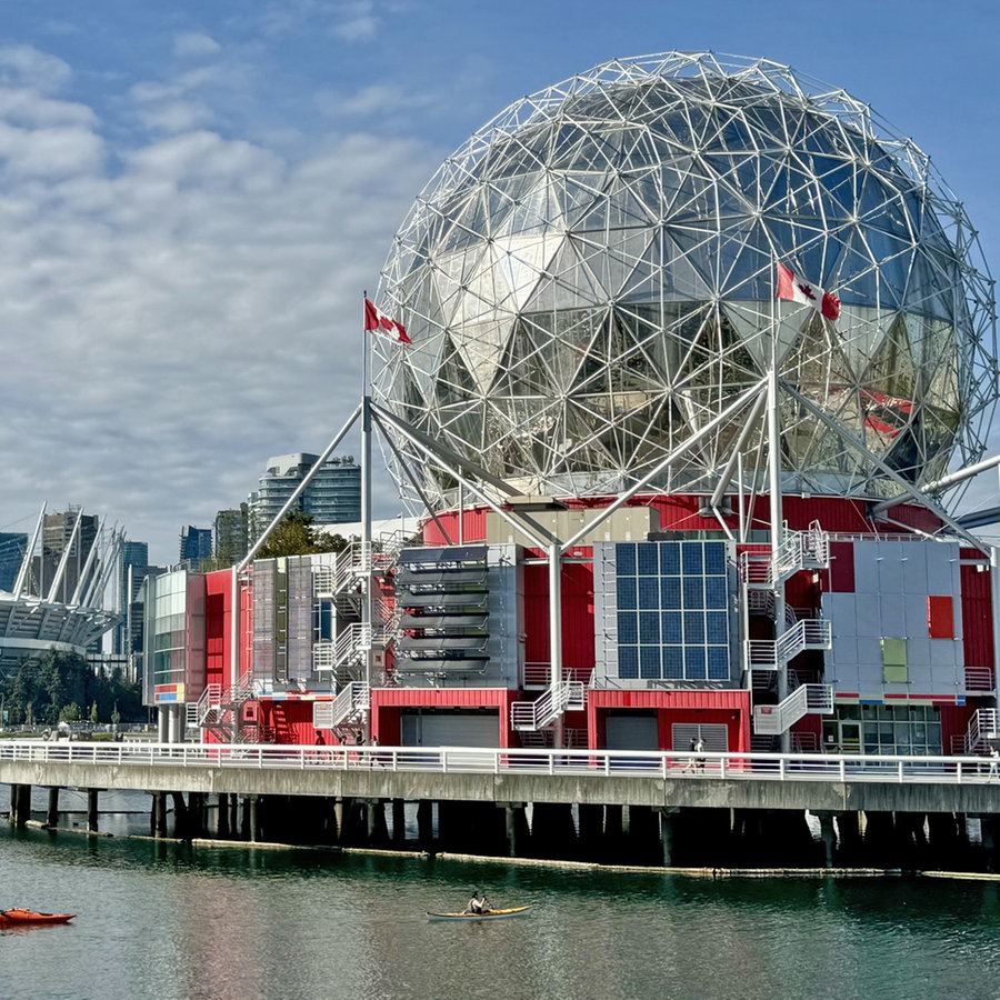 Ein kugelförmiges Gebäude direkt am Wasser, dahinter die Skyline von Vancouver mit Stadion © NDR Foto: Dennis  Burk