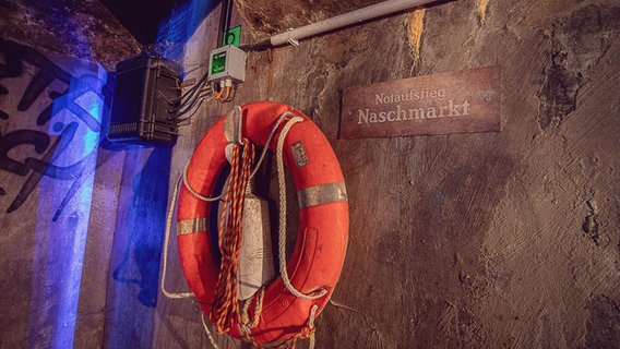 Ein Rettungsring hängt an der Wand der Kanalisation in Wien, daneben ein Schild: "Notaufstieg Naschmarkt" © NDR Foto: Michael Marek