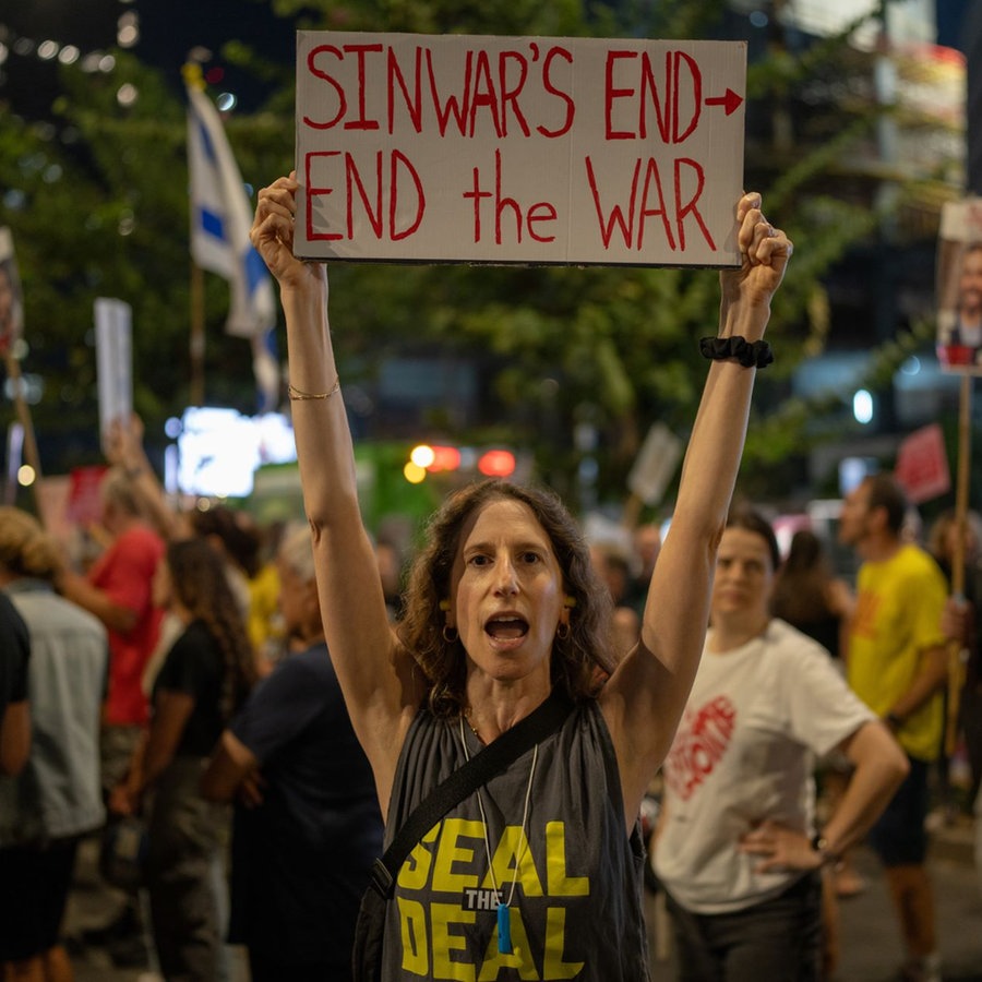 Eine Frau hält ein Schild hoch mit der Aufschrift "Sinwar's End - end the war" und fordert mit anderen die Freilassung der israelischen Geiseln, nachdem bekannt wurde, dass Hamas-Chef Jahia Sinwar getötet wurde. © picture alliance/dpa | Ilia Yefimovich Foto: Ilia Yefimovich