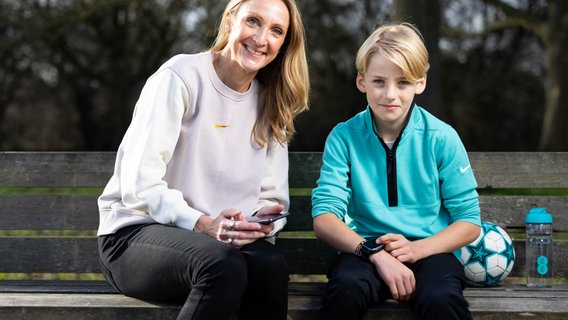 Mutter und Sohn sitzen auf einer Bank, der Junge zeigt auf seine Smartwatch © picture alliance / empics | David Parry Foto: David Parry