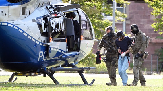 Karlsruhe: Der mutmaßliche Täter des Messerangriffs von Solingen wird zu einem Hubschrauber gebracht. Zuvor war der Verdächtige dem Ermittlungsrichter beim Bundesgerichtshof (BGH) vorgeführt worden, der Haftbefehl erließ. © dpa Foto: Uli Deck