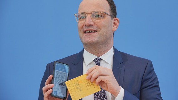 Jens Spahn (CDU), Federal Minister of Health, shows the Corona Warn app with a sample of a digital vaccination certificate and his own old vaccination pass at the regular press conference on the Corona situation.  © dpa-Bildfunk Photo: Michael Kappeler