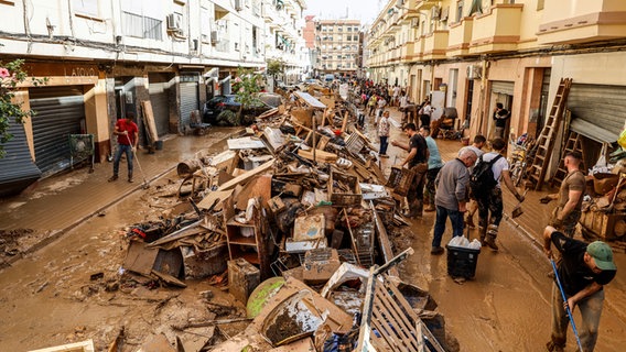 In Paiporta, einem Vorort von Valencia, beseitigen Menschen die durch Unwetter verursachten Schäden. Noch immer stapeln sich vielerorts Autos, ganze Orte sind mit Schlamm überzogen und von der Außenwelt abgeschnitten - die Aufräumarbeiten in Spanien werden wohl lange Zeit in Anspruch nehmen. © Rober Solsona/EUROPA PRESS/dpa 