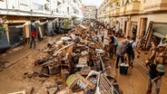 In Paiporta, einem Vorort von Valencia, beseitigen Menschen die durch Unwetter verursachten Schäden. Noch immer stapeln sich vielerorts Autos, ganze Orte sind mit Schlamm überzogen und von der Außenwelt abgeschnitten - die Aufräumarbeiten in Spanien werden wohl lange Zeit in Anspruch nehmen. © Rober Solsona/EUROPA PRESS/dpa 