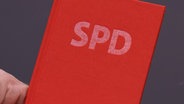 Eine Hand zeigt ein SPD-Parteibuch. © David Young/dpa 