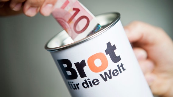 Eine Hand steckt einen Zehn-Euro-Schein in eine Spendendose für "Brot für die Welt" © Hermann Bredehorst/Brot für die Welt 