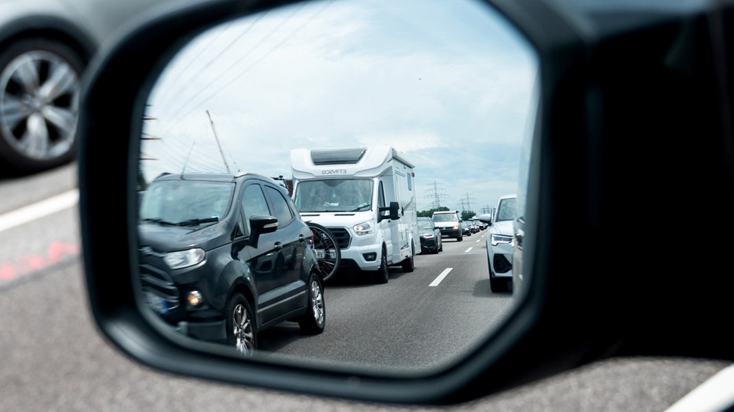 Reiseverkehr steht auf der Autobahn A7 vor dem Elbtunnel in Richtung Norden im Stau und spiegelt sich im Rückspiegel eines Autos.
