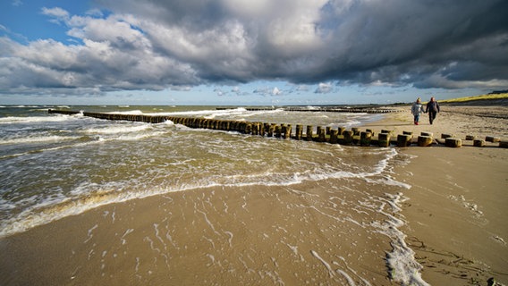 Zwei Menschen spazieren an einem stürmischen Tag am Ostseestrand in Ahrenshoop. © picture alliance / imageBROKER | Michael Nitzschke Foto: Michael Nitzschke