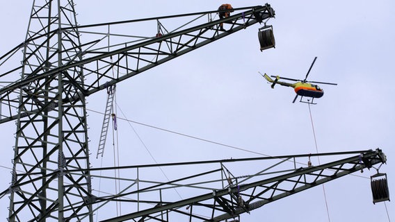 Ein Helikopter zieht bei Gudow an der Autobahn A 24 ein Vorseil von einem Starkstrommast zum nächsten. © dpa-Bildfunk Foto: Jens Büttner