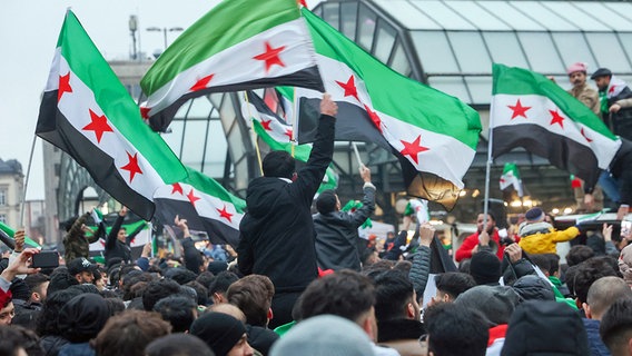 Zahlreiche Menschen feiern am Hachmannplatz am Hauptbahnhof den Sturz von Syriens Machthaber Assad. © dpa bildfunk Foto: Bodo Marks