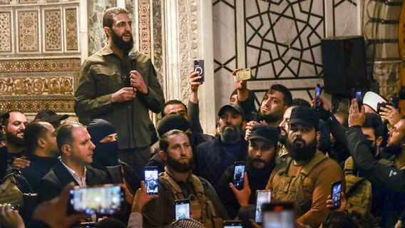 Abu Mohammed al-Dschulani, Anführer der größten Rebellengruppe in Syrien spricht in der Umayyaden-Moschee in Damaskus. © Omar Albam/AP 