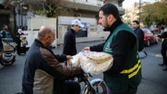 Eine örtliche humanitäre Organisation verteilt Brot an Menschen in den Straßen von Damaskus. © Juma Muhammad/IMAGESLIVE via ZUMA Press Wire/dpa 