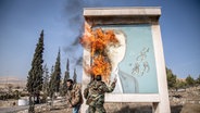 Damaskus: Ein Mann entzündet ein Bild des ehemaligen syrischen Präsidenten Bashar al-Assad in der Nähe der syrischen Grenze zum Libanon. © Sally Hayden/SOPA Images via ZUMA Press Wire/dpa Foto: Sally Hayden