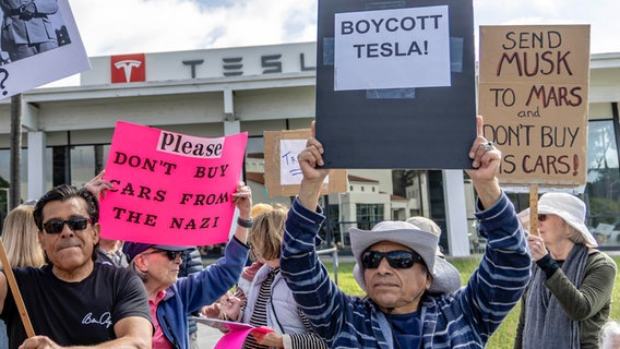 Protestanten vor einem Tesla-Laden von Elon Musk fordern einen Boykott von Tesla und ein Ende seiner versuchten Regierungsübernahme. © picture alliance / Sipa USA Foto: Rod Rolle