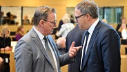 Bodo Ramelow (l., Die Linke), geschäftsführender Ministerpräsident von Thüringen, und Mario Voigt (r), CDU-Partei- und Fraktionschef von Thüringen, sprechen miteinander vor einem Festakt im Thüringer Landtag. © picture alliance Foto: Martin Schutt