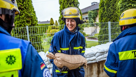 Einsatzkräfte des Technischen Hilfswerks transportieren Sandsäcke mit einer Menschenkette. © THW Foto: Nicole Endres