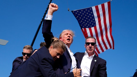 Donald Trump reckt nach dem Attentat auf ihn eine Faust hoch. © Evan Vucci/AP/dpa Foto: Evan Vucci