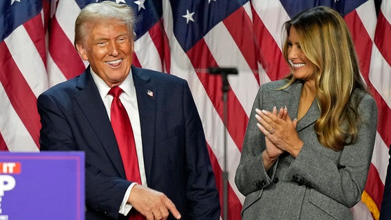 Der Republikaner Donald Trump (l.) und die ehemalige First Lady Melania Trump nach der US-Wahl auf einer Bühne. © dpa bildfunk/AP Foto: Alex Brandon