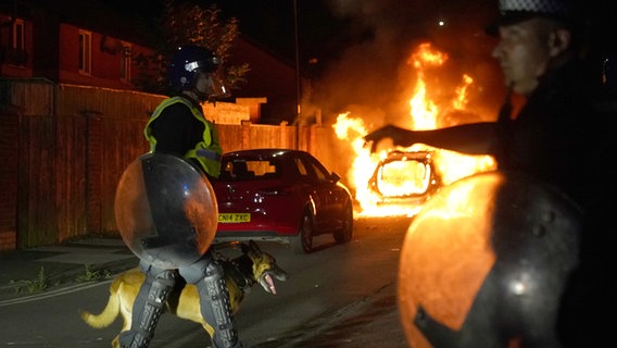 Ein Polizeiauto brennt, als Beamte nach einem gewalttätigen Protest in den Straßen von Hartlepool eingesetzt werden. © PA Wire/dpa Foto: Owen Humphreys