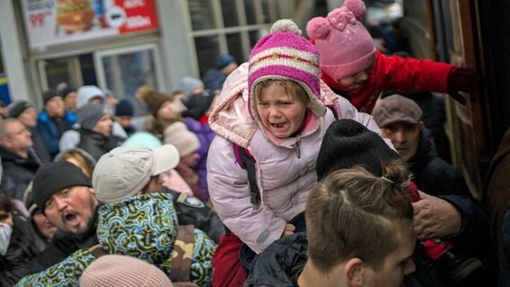 Menschen tragen ihre Kinder und versuchen am Bahnhof von Kiew in einen Zug nach Lwiw zu steigen. © dpa-Bildfunk 