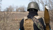 Ein ukrainischer Soldat mit Zeichnungen auf seinem Helm trägt eine Panzerabwehrwaffe. © dpa Bildfunk/ZUMA Press Wire Foto: Andrea Filigheddu