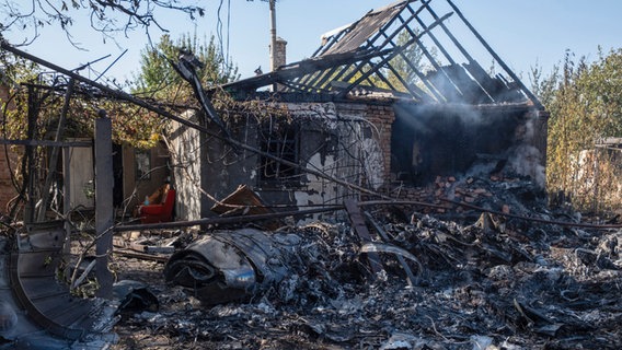 Ein beschädigtes Haus ist im Hintergrund von Fragmenten eines abgeschossenen russischen Militärflugzeugs am Stadtrand von Kostjantyniwka, einer Stadt nahe der Frontlinie in der Region Donezk, zu sehen. © Iryna Rybakova/AP 