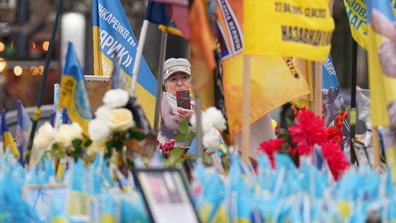 Eine Frau macht ein Foto an einem Denkmal für die Gefallenen des Kriegs mit Russland auf dem Unabhängigkeitsplatz in Kiew. © dpa-Bildfunk/PA Wire Foto: Stefan Rousseau