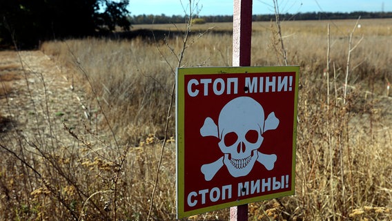 Ein Warnschild "Stop! Minen" steht an einem Feld in der Ukraine. © dpa picture alliance/Ukrinform 