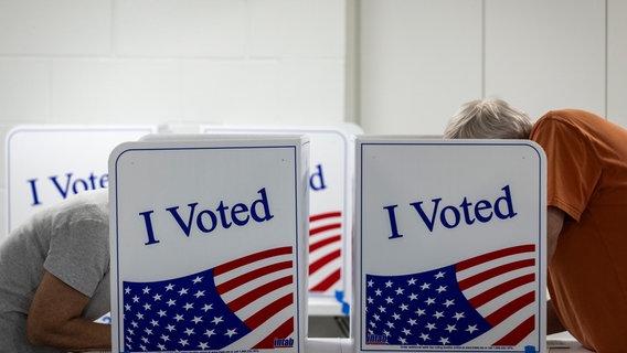 Zwei Menschen bei der Stimmabgabe zur US-Präsidentschaftswahl in einem Wahllokal. © dpa picture alliance / Sipa USA 