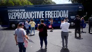 Menschen fotografieren den Bus bei einer Auftaktveranstaltung zur "Reproductive Freedom Bus Tour", der Kampagne der demokratischen Präsidentschaftskandidatin Harris. © picture alliance/dpa/AP | Rebecca Blackwell 