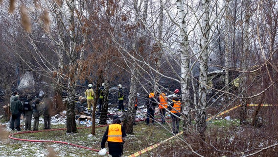 Mitarbeiter des litauischen Katastrophenschutzministeriums arbeiten in der Nähe der Stelle, an der ein DHL-Frachtflugzeug in ein Haus in der Nähe der litauischen Hauptstadt Vilnius, Litauen, gestürzt ist. © Mindaugas Kulbis/AP 