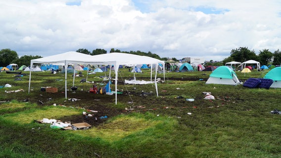 Eine Wiese mit Zelten, Pavillons und allerelei Abfall © NDR Foto: Janine Artist