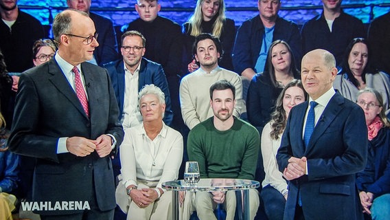 Friedrich Merz (l.), Unions-Kanzlerkandidat und CDU-Bundesvorsitzender, und Bundeskanzler Olaf Scholz (SPD) sind gemeinsam auf einem Bildschirm während der Sendung ARD "Wahlarena" zu sehen. © Kay Nietfeld/dpa 