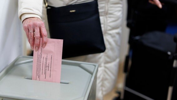 Eine Frau steckt den Wahlschein in eine Urne © Christoph Reichwein/dpa 