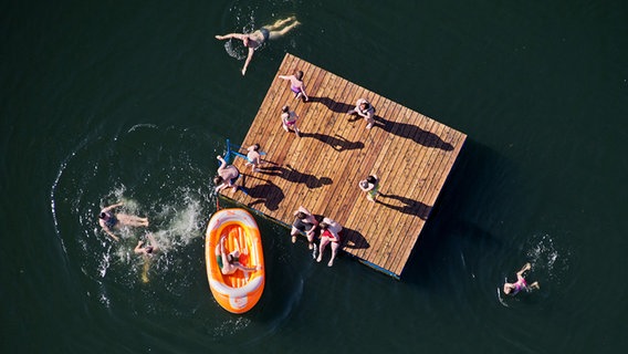 Ein Steg und schwimmende Menschen von oben im Wasser sind zu sehen. © dpa-Bildfunk Foto: dpa-Bildfunk