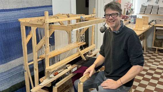 Andreas Möller sitzt an einem Webstuhl in der Weberei Hamburg. © NDR Foto: Anina Pommerenke