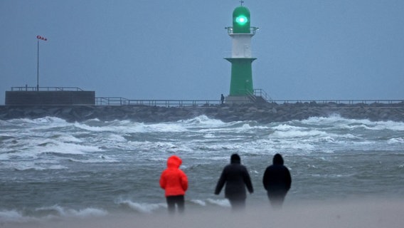 Spaziergänger sind bei Regen und Sturmböen am Ostseestrand bei Rostock unterwegs (Archivbild) © Bernd Wüstneck/dpa Foto: Bernd Wüstneck