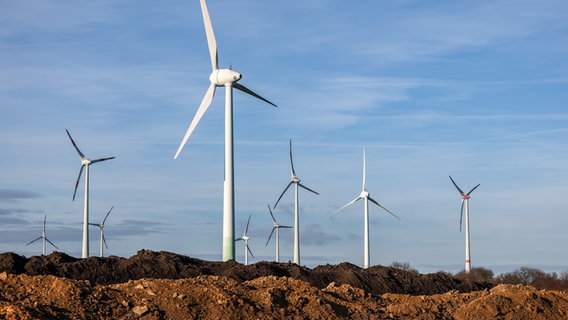 Windräder stehen hinter Erdhaufen am Rande eines Baufelds. © picture alliance/dpa | Jan Woitas 