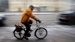 Ein Fahrradfahrer fährt bei Eisregen über einen glatten Radweg in Hamburg. 