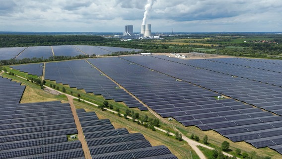 Hinter den Modulen des 650-Megawatt-Solarparks Witznitz ist das Braunkohlekraftwerk Lippendorf zu sehen © Hendrik Schmidt/dpa Foto: Hendrik Schmidt/dpa