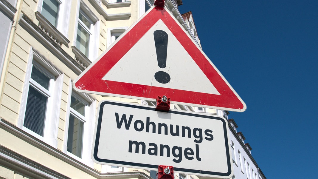 Ein Baustellenschild mit der Aufschrift "Wohnungsmangel" vor einer Hausfassade © picture alliance / SULUPRESS.DE Foto: Torsten Sukrow / SULUPRESS.DE