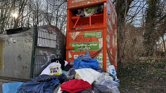 Ein Altkleidercontainer steht neben einem Glascontainer, einige Säcke mit Kleidung liegen davor. © NDR Foto: Axel Krummenauer