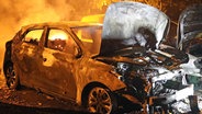 Die Motorhaube eines brennenden Autos ist aufgeklappt, hinten schlagen aus dem Fahrzeug Flammen. © Stefan Tretropp Foto: Stefan Tretropp