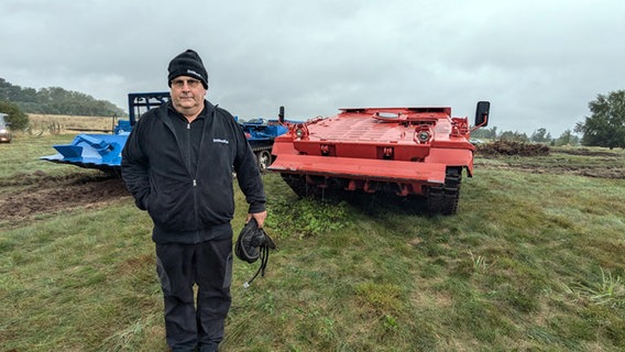 Joachim Schulz steht vor einem sowjetischen T-55 und einem Schützenpanzer "Marder", die eigentlich zu Brandschutzzwecken eingesetzt werden. © Chris Loose Foto: Chris Loose