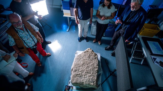 Einen etwa 900 Jahre alten und vor wenigen Tagen ausgegrabenen Bildstein stellen Landesarchäologe Detlef Jantzen (r), Bettina Martin (M, SPD), die Wissenschafts- und Europaministerin von Mecklenburg-Vorpommern, bei einem Pressetermin im Landesamt für Kultur und Denkmalpflege vor. © dpa Foto: Jens Büttner