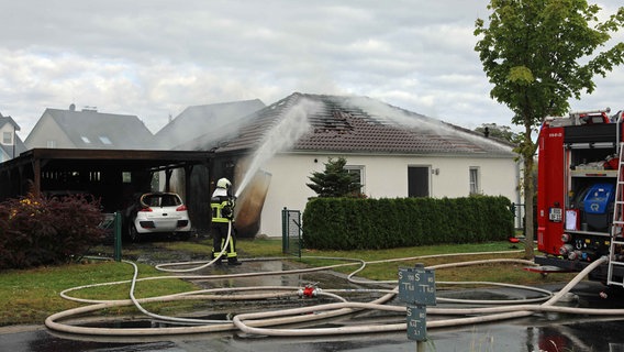 Ein Feuerwehrmann löscht ein brennendes Haus in einem Wohngebiet. © Stefan Tretropp Foto: Stefan Tretropp