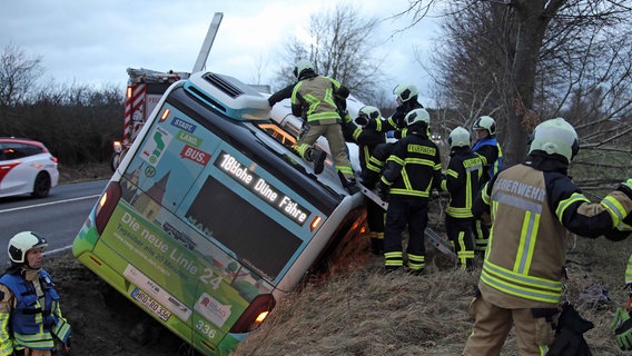 Feuerwehrkräft retten Menschen über die Dachluke eines Busses, der im Straßengraben liegt. © NDR, Stefan Tretropp Foto: Stefan Tretropp