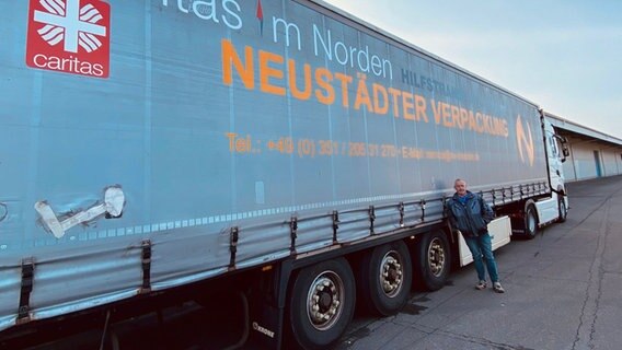 Mann steht vor Lkw, der Hilfsgüter in die Westukraine fahren wird. 